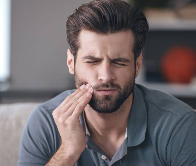 Man grimacing due to mouth pain