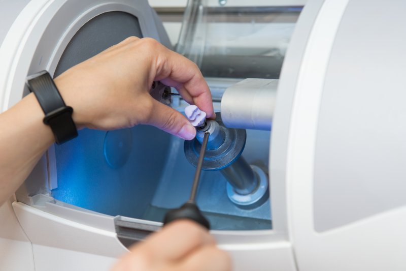 A woman making a dental crown with a CEREC machine